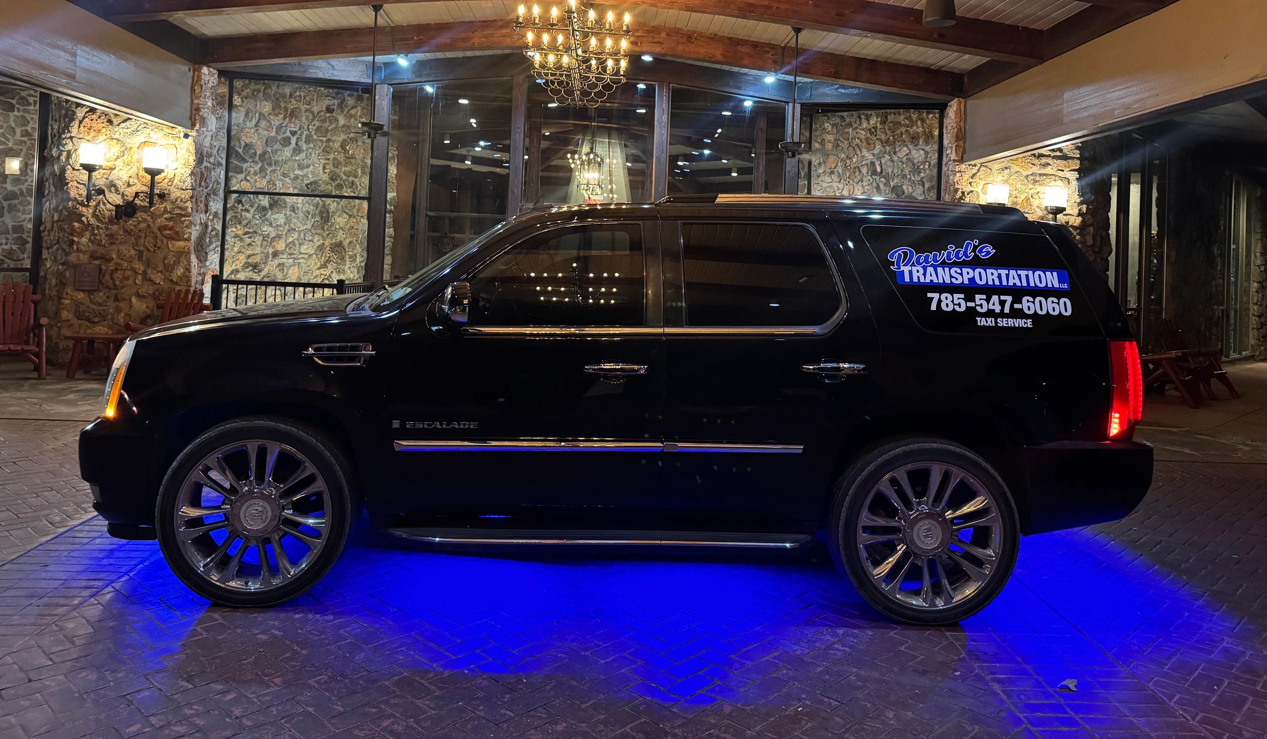 Black luxury SUV with blue underglow lighting at sunset