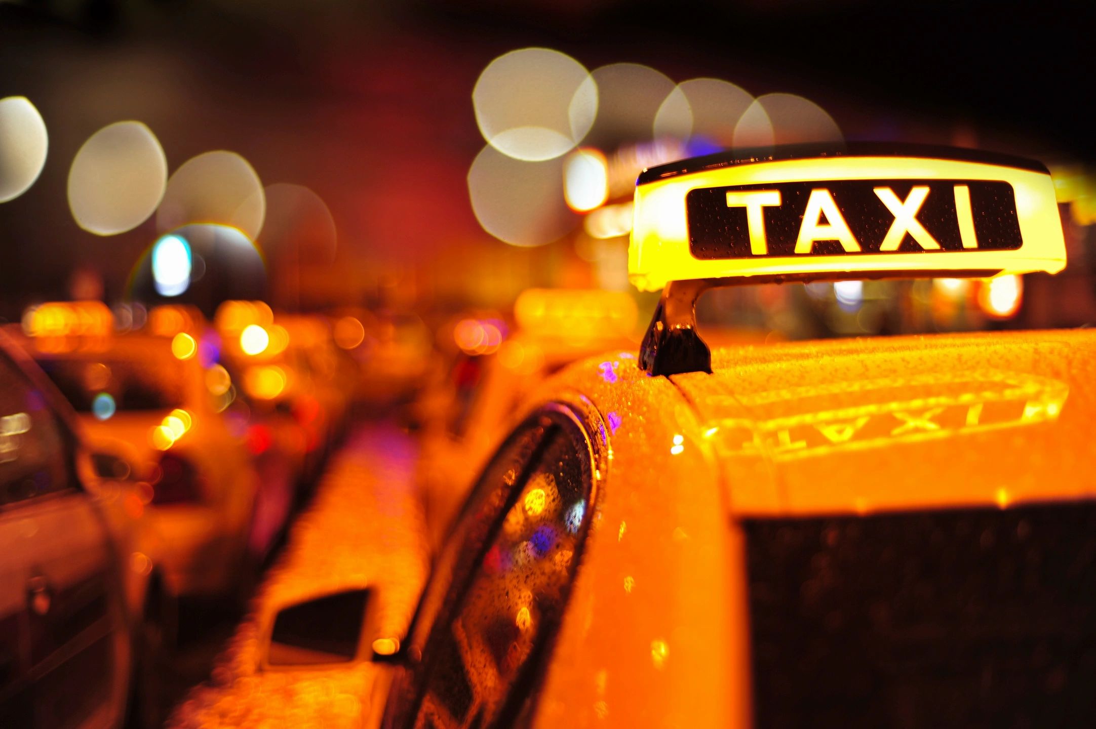 Yellow taxi cab at night with city lights