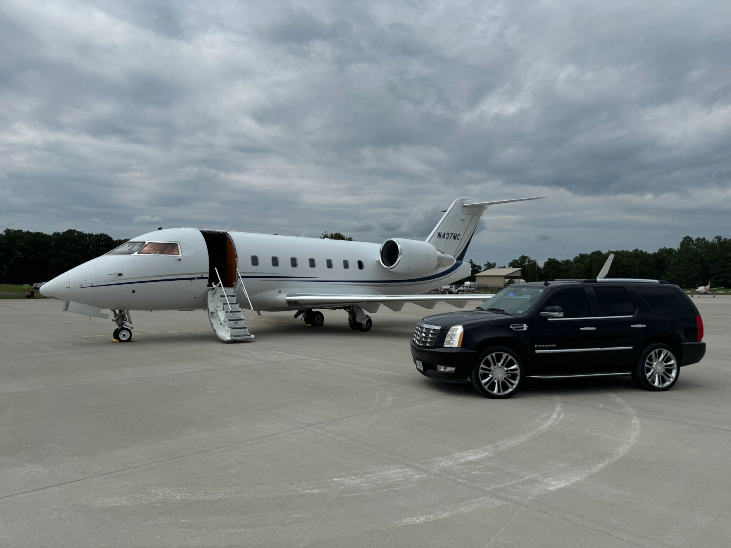 Luxury private jet with black Cadillac Escalade on airport tarmac